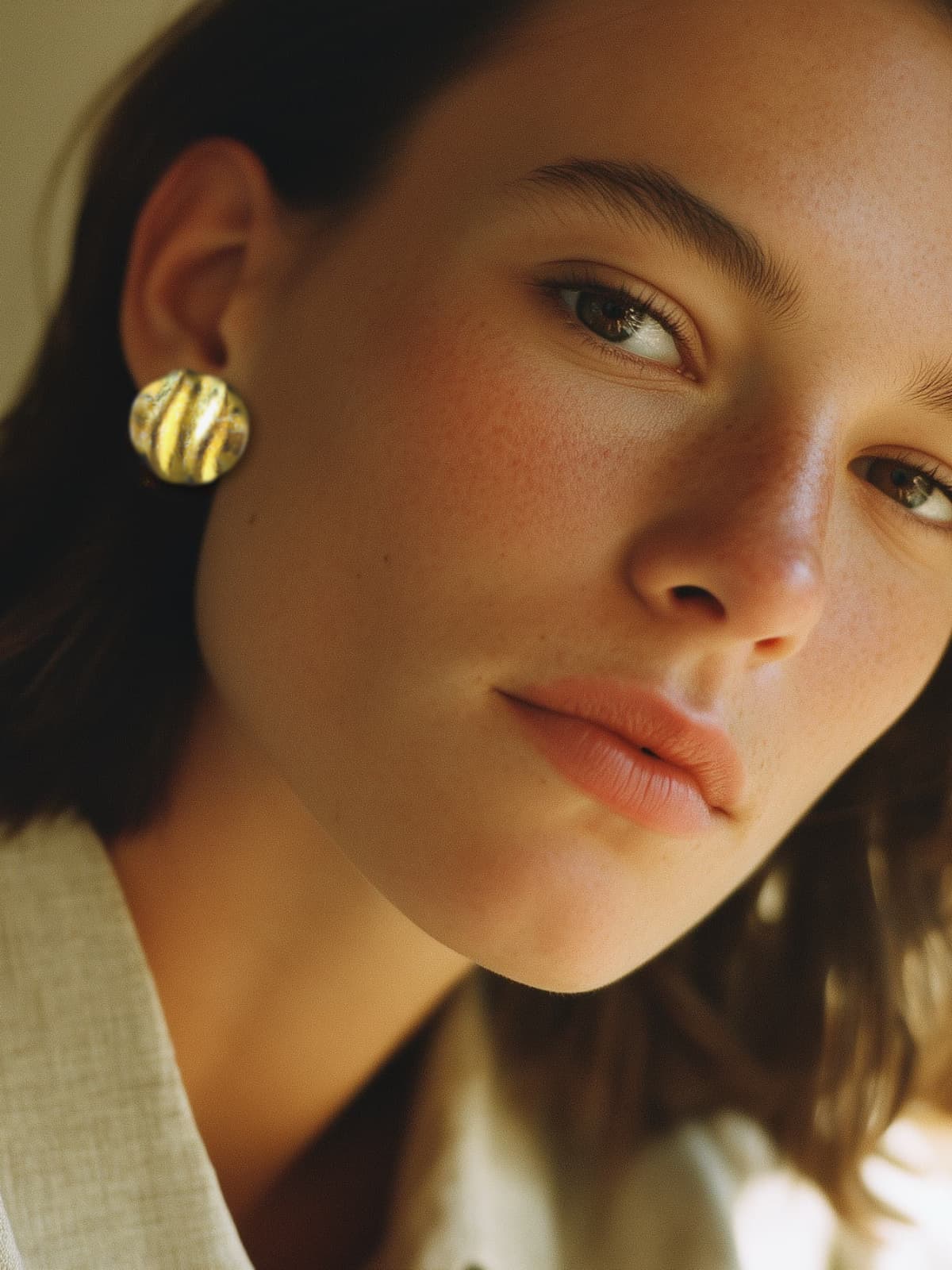 Woman wearing gold earrings looking at a screen with a warm glow